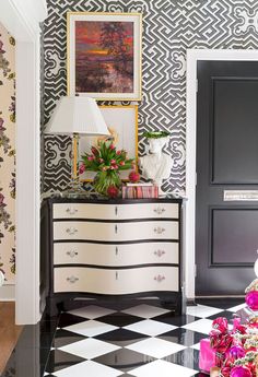 a black and white checkered floor in a living room with flowers on the dresser