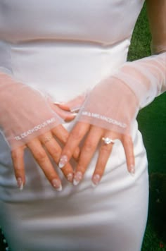 a woman with her hands in the shape of a heart on her wedding day, wearing white gloves