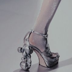 a woman's silver high heeled shoes with a teddy bear on the side