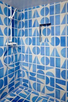 a bathroom with blue and white tiles on the shower head, hand held shower arm