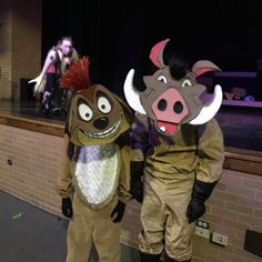 two people in animal costumes standing next to each other on a stage with brick walls