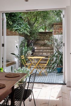 an open patio with yellow chairs and table in the middle, surrounded by greenery