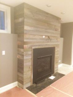 an empty room with a fireplace in the middle and wood paneling on the wall