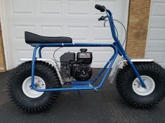 a small blue motorcycle parked in front of a garage