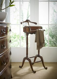 an old fashioned wooden table with a cloth on it's stand in front of a window