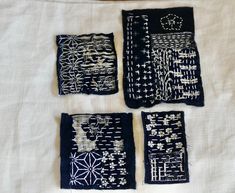 four pieces of cloth with designs on them sitting on a white tablecloth next to each other