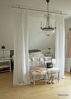 a bedroom with a chandelier hanging from the ceiling next to a white bed