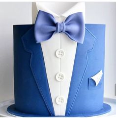 a blue and white cake decorated with a tuxedo, bow tie and button