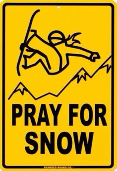 a yellow sign that says pray for snow with a man falling down the mountain behind it