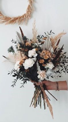 a person holding a bouquet of flowers in their hand and two wreaths on the wall behind them