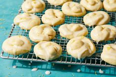 a cooling rack filled with frosted cookies on top of a blue table