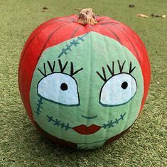 a painted pumpkin sitting on top of a green field