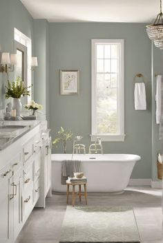 a white bath tub sitting under a window in a bathroom