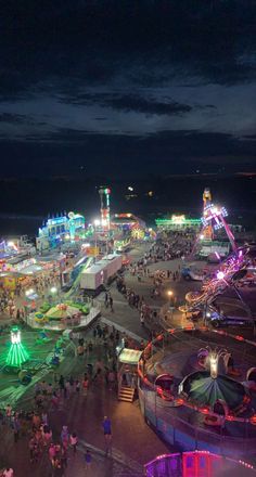 an aerial view of a fairground at night with people walking around and rides on the ground