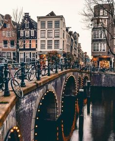 bicycles are parked on the side of an old bridge over a river in a city