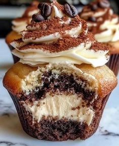 cupcakes with white frosting and chocolate chips on top are sitting on a marble surface