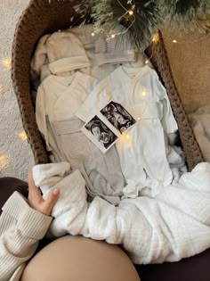 a woman sitting in a chair with clothes on top of her and a christmas tree behind her