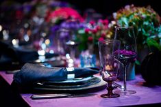 the table is set with glasses, plates and napkins