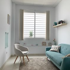 a living room with a blue couch, chair and window in the corner next to it