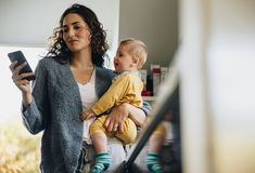 a woman holding a baby while looking at a cell phone