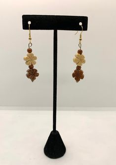 Handcrafted wooden flower shaped earrings are beige and brown with 2 small wooden beads in between. These earrings measure 2 1/2" from top of earwire to bottom and have a 1 1/2" dangle. Brown Flower Earrings With Ear Wire, Brown Dangle Flower Earrings For Pierced Ears, Brown Dangling Beads Earrings For Gift, Brown Flower Drop Earrings, Brown Flower Earrings, Brown Flower-shaped Earrings For Gift, Adjustable Brown Earrings With Wooden Beads, Brown Dangle Flower Earrings, Brown Bohemian Drop Flower Earrings