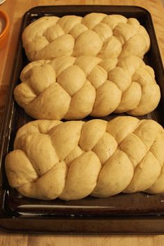 two loaves of bread sitting on top of a baking pan next to a bowl