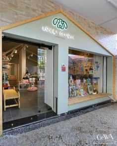 a store front with an open door and window displays books on the outside, along with a brick wall