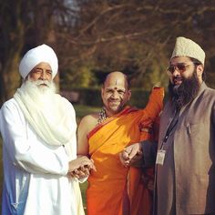 three men standing next to each other with one holding the other's hand and smiling