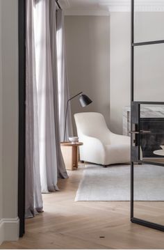 a living room with a white chair and a black lamp on the side of the wall