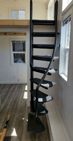 there is a spiral staircase in the middle of a room with wood flooring and white walls