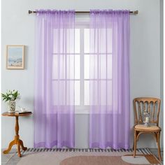 purple sheer curtains hanging on a window in a living room with a table and chair