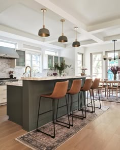 a kitchen with an island and bar stools in the center, surrounded by wooden flooring