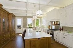 a large kitchen with white cabinets and wood flooring on the walls, along with an island in the middle