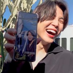 a person holding up a cell phone in front of their face and smiling at the camera