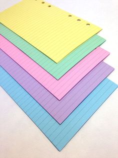 five lined notebooks are stacked on top of each other, with holes in the middle