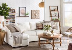 a living room with white couches and pictures on the wall above them, along with a coffee table