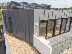 an aerial view of a modern home with glass doors and metal sidings on the roof