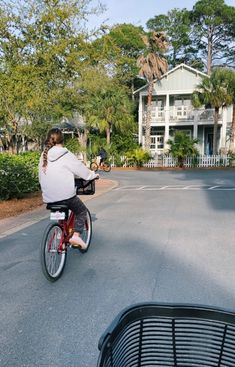 a person riding a bike down a street next to a fence and palm trees in front of a large white house