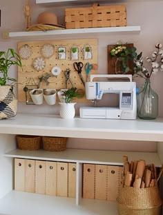 a sewing machine sitting on top of a white shelf next to some baskets and flowers