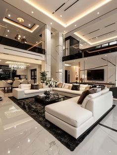 a large living room with white couches and black rugs on the floor is lit by recessed lights