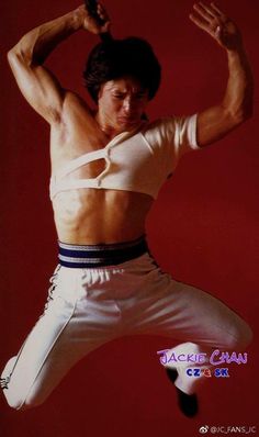 a man in white shirt and pants doing a kick with his arms out to the side