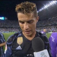 a soccer player holding a microphone in front of his face and talking to the media