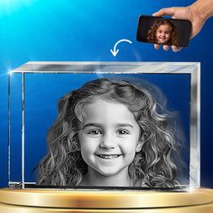 a person holding a cell phone up to a photo frame with a child's face on it