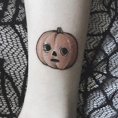 a person with a small tattoo on their leg that has a pumpkin shaped face drawn on it