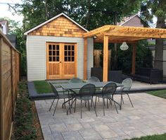 a backyard with a table and chairs next to a shed