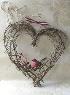 a bird sitting on top of a heart shaped decoration with branches and berries hanging from it