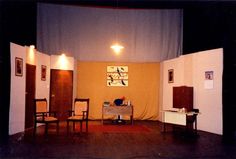 an empty room with two chairs and a table in front of a curtained wall