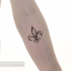 a small black and white fleur de lis tattoo on the arm