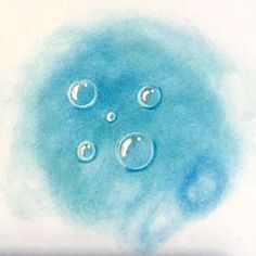 three water droplets are shown in the center of a blue circle on a white surface