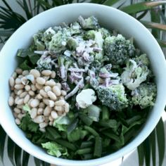 a white bowl filled with broccoli, beans and other vegetables on top of a table